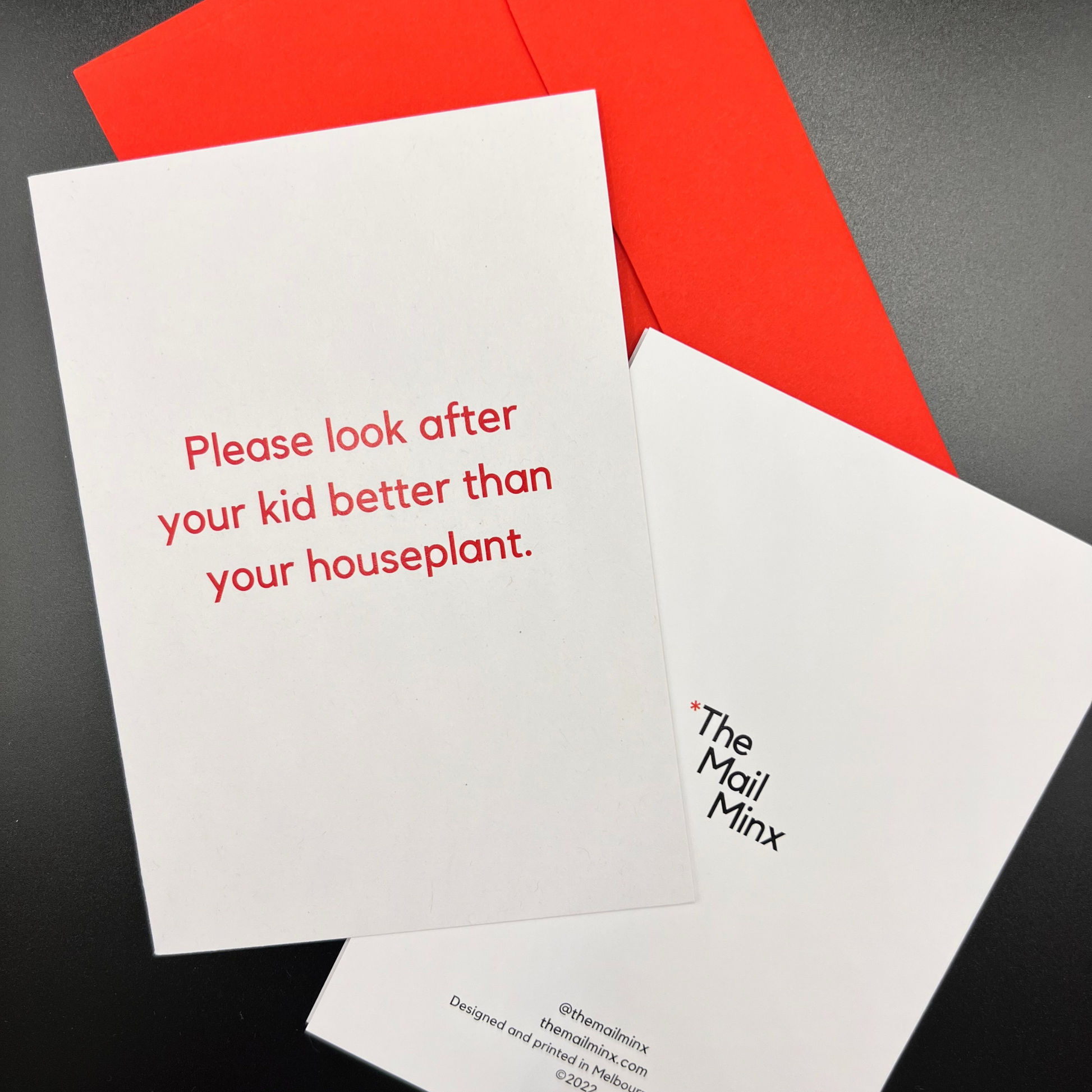 The Mail Minx baby shower greeting card that is white and says "Please look after your kid better than your houseplant" in red text. The back of the card shows The Mail Minx logo and there is a red envelope in the background.