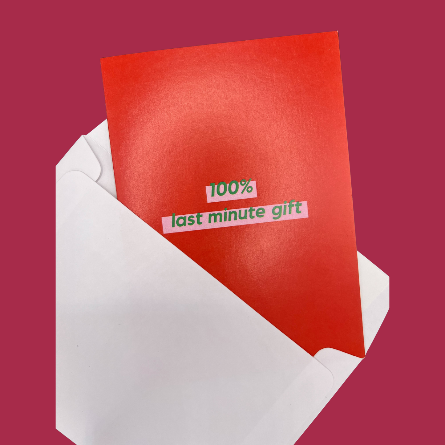 A red greeting card by The Mail Minx with a message saying "100% last minute gift" in green text, highlighted in pink - card is popping out of a white envelope