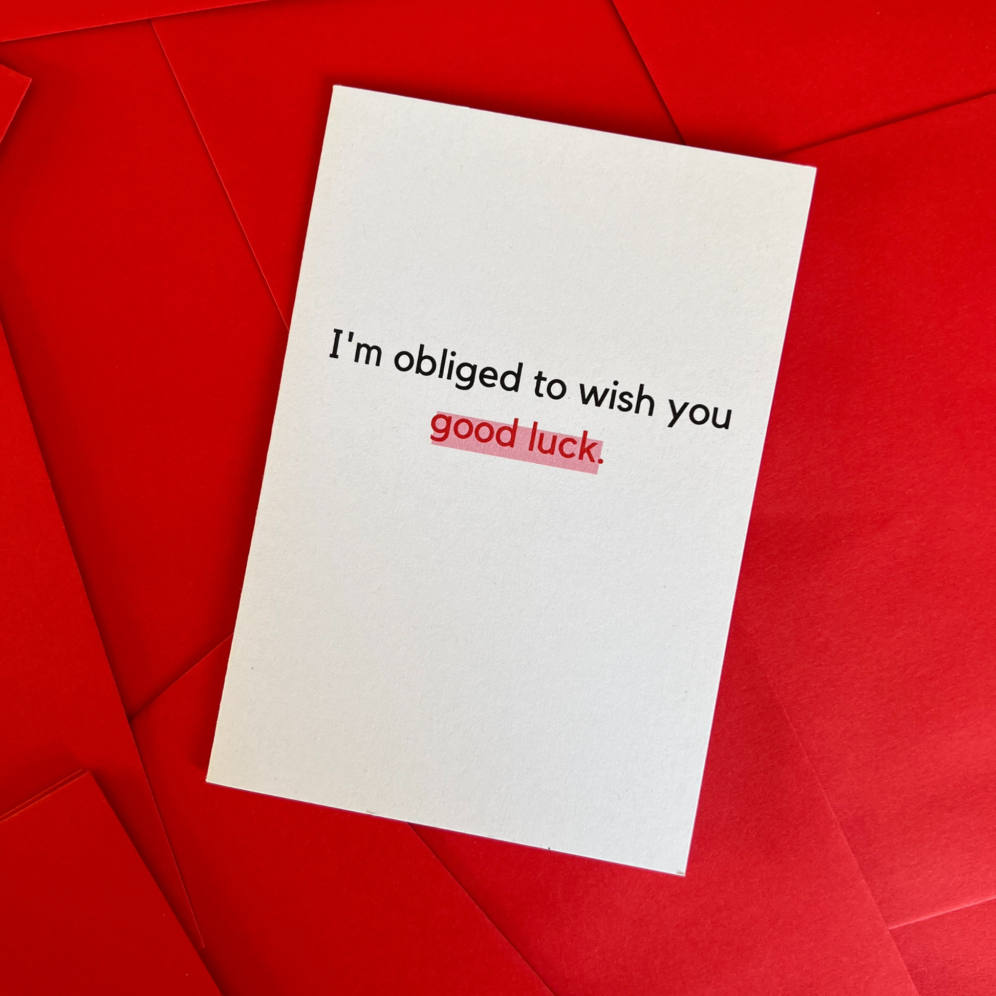The Mail Minx good luck greeting card that is white and says "I'm obliged to wish you good luck." in black and red text.