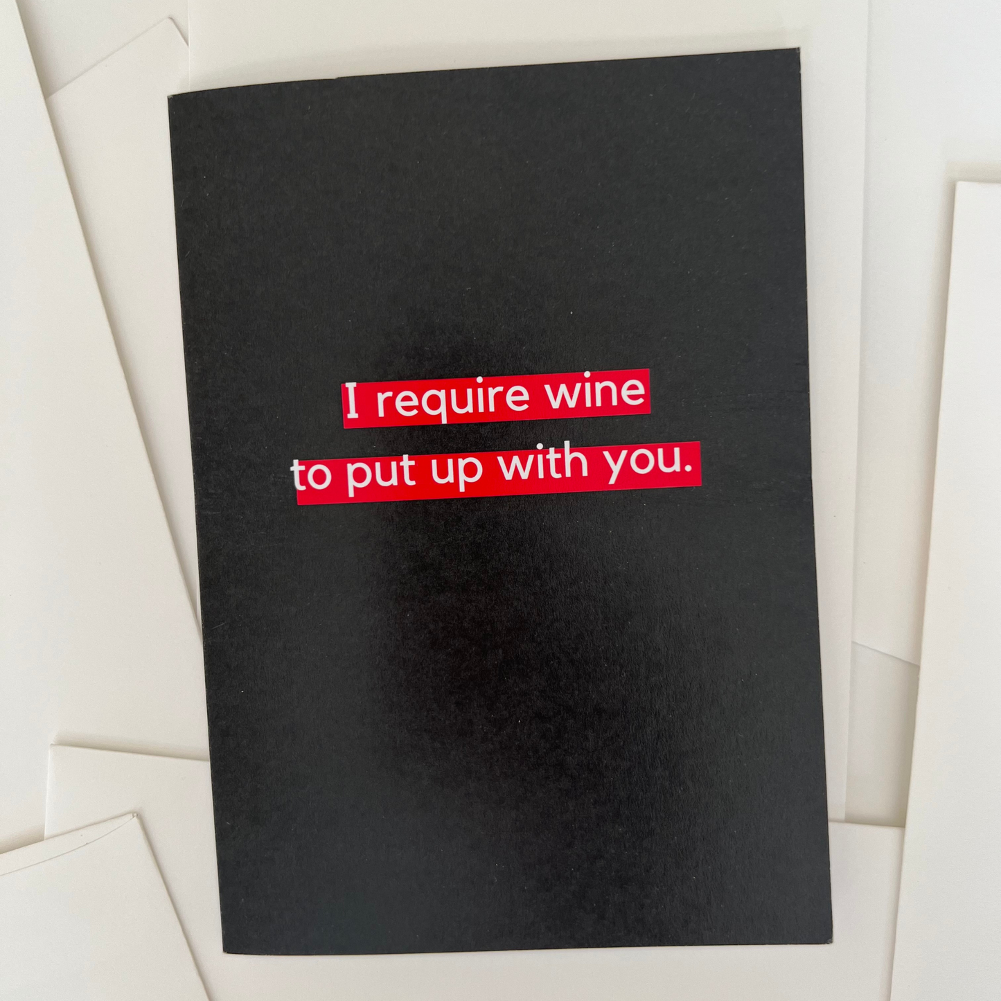 The Mail Minx greeting card that is black and says in white text highlighted in red "I require wine to put up with you."