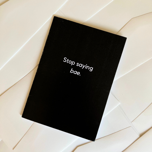 A black greeting card by The Mail Minx saying "Stop saying bae" in black text.