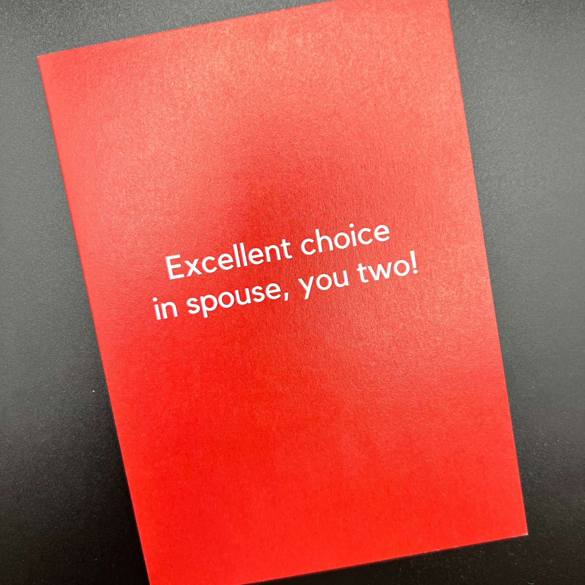 A red greeting card that says "Excellent choice in spouse, you two!" in white text, designed by The Mail Minx