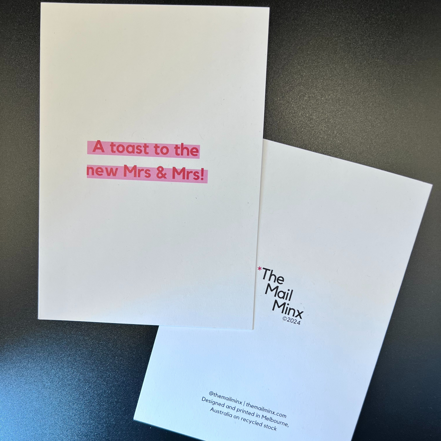 The front and back of a lesbian wedding greeting card designed by The Mail Minx that says a toast to the mrs and mrs